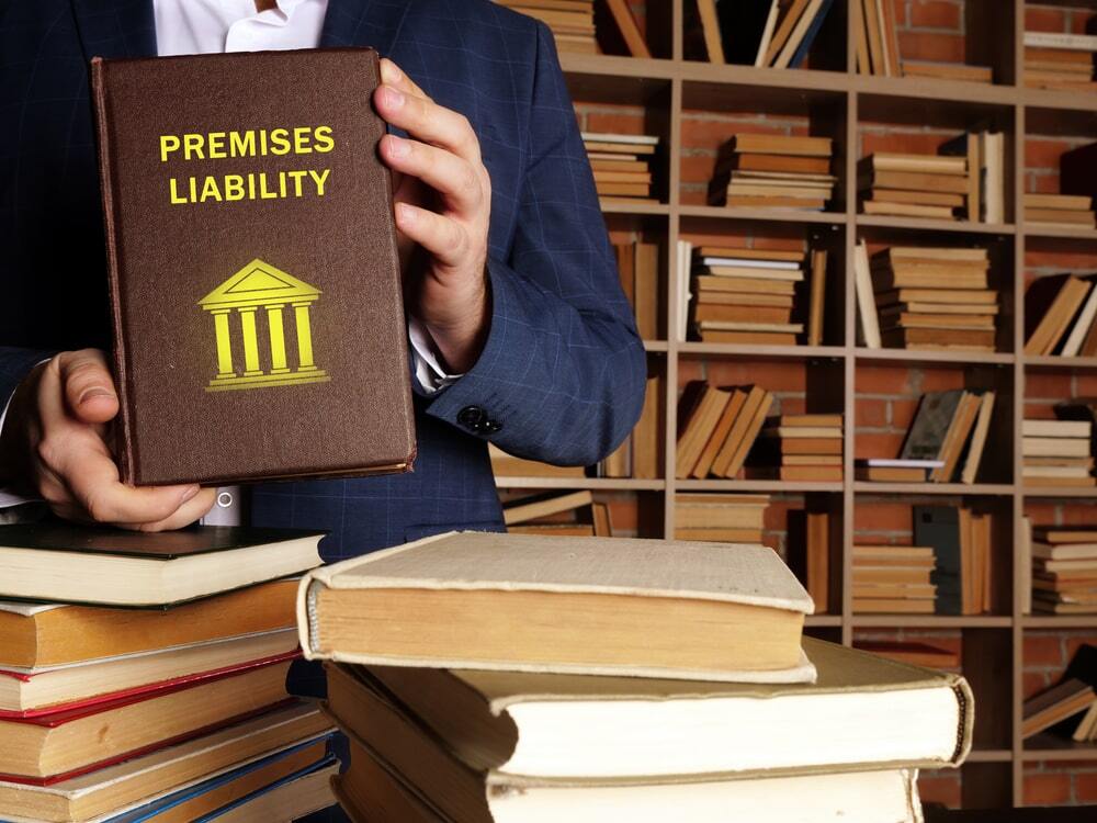 Man in suit holding a Premises Liability law book in a library